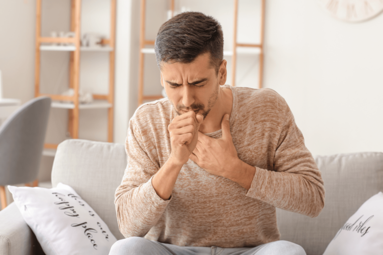 man coughing at home from poor indoor air quality