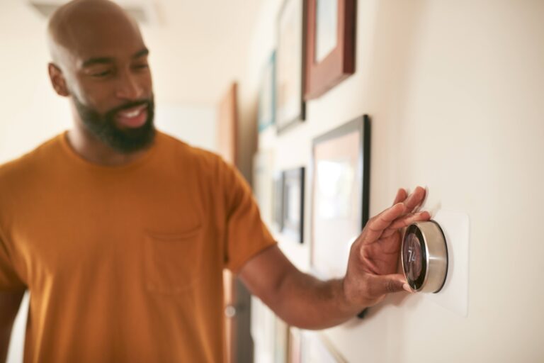 A man adjusting the thermostat in a home.