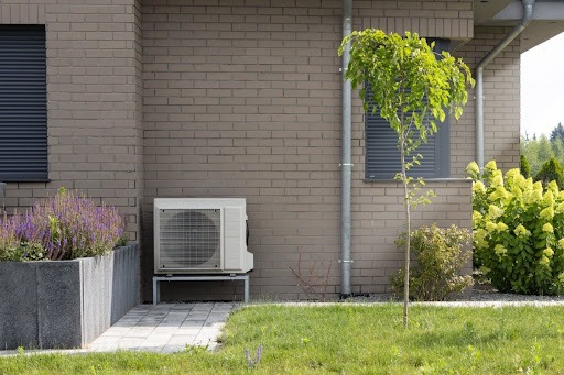 An outdoor heat pump unit installed near the exterior of a house.