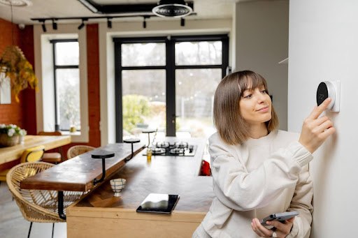 Woman adjusting thermostat to heat.