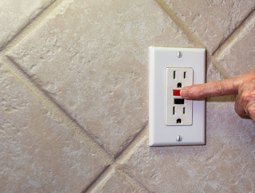 A finger pressing a reset button on a GFCI outlet.