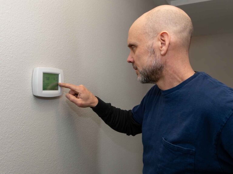 Home inspector examining a home thermostat near living room.
