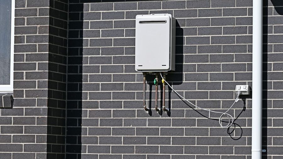 Tankless water heater mounted to a brick wall